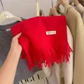 Close-up of a premium red knitted winter scarf featuring soft fringe and label - 194cm / Bright Red Series
