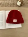 Rote flauschige Strickmütze mit Bella-Logo-Patch auf einem offenen Buch für den Winter - Einheitsgröße / Neujahrsrot