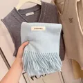 Detailed close-up of a soft light blue knitted scarf with fringes and a woven label - 194cm / Baby Blue