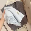 Detailed view of a soft light blue knitted scarf featuring classic tassels and tag. - 194cm / Azure Blue