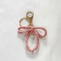 Handmade pink crocheted bow keychain with elegant pearl charm for bag decoration - Pink