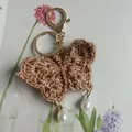 Handmade crochet butterfly keychain with pearl drops and golden lobster clasp for bags. - Coffee