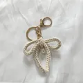 Handmade woven cotton bow keychain with white pearl pendant and gold lobster clasp - Beige