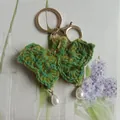 Handmade green crochet butterfly keychain with elegant pearl drops and gold metal clasp - Dark Green