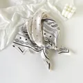 Elegant cream silk-feel scarf featuring a black paisley pattern and knotted detail - Starry Sky Paisley - White