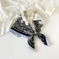 Detailed view of elegant navy blue paisley print silk scarf tied in a decorative knot - Twin Paisley - Blue & Beige