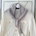 Detailed close-up of an elegant light grey pleated silk scarf with pink contrast piping. - 60CM / Gray