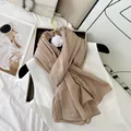 Detailed view of a premium beige crinkled cotton blend scarf with white flower brooch - Nude