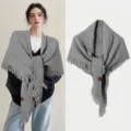 Detailed macro view of a grey knitted triangular shawl with fringe and small leather tag - Gray