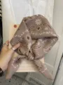 Lightweight cotton linen square scarf with brown paisley floral pattern tied on a book - Leaf Frame Paisley / Khaki