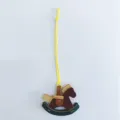 Detailed view of a handcrafted leather rocking horse bag charm with yellow cord - Yellow