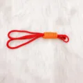 Red handmade braided keychain lanyard with orange wrap detail on white faux fur background - Red