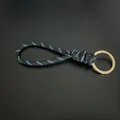 Hand-woven black cord keychain with blue dots and a golden metal ring. - Black