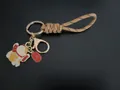 Hand-woven tan wrist strap keychain featuring a lucky cat charm and blessing tag - Caramel color
