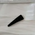 Vue détaillée d'une pince à cheveux noire à pois blancs sur un tissu scintillant - Barrette Triangle à Pois / Noir