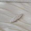 Vue détaillée d'une barrette ovale blanche à pois noirs sur un tissu scintillant - Barrette Ovale à Pois / Beige