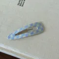 Primo piano di un fermaglio per capelli a scacchi blu e bianchi su superficie crema - A quadri / Giallo Blu Goccia d'Acqua