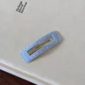 Primo piano di un fermaglio per capelli in tessuto a pois azzurro su superficie testurizzata - Pois / Blu Quadrato