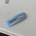 Dettaglio del fermaglio per capelli in tessuto azzurro su una superficie ruvida - Tinta unita / Blu Quadrato