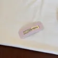 Gros plan d'une pince à cheveux rose à pois sur une surface en tissu blanc doux - Style Creux Carré / Rose à Pois