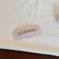 Vue macro d'une pince à cheveux à rayures roses en tissu avec un design évidé - Style Creux Carré / Carreaux Rose
