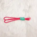 Handmade pink and teal braided keychain rope on white fluffy background - Pink