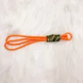 Handmade orange braided paracord keychain with camouflage detail on white fur background - Orange