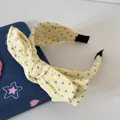 Détail d'un serre-tête en tissu jaune avec motifs d'étoiles grises et nœud papillon - Style Nœud Étoile / Jaune