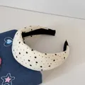 Détail du serre-tête rembourré crème avec motif d'étoiles noires et tissu texturé. - Style Étoile Large / Beige