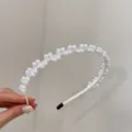 Detailopname van een elegante haarband met witte kralen en stoffen omwikkeling - Parelstijl