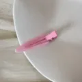 Vue détaillée d'une pince à cheveux rose avec texte fait main sur une assiette blanche - Clip Triangulaire Sans Trace (FJ83071) / Rose