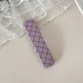 Gros plan d'une pince à cheveux en tissu à carreaux violet et marron sur dentelle - Pince Carrée à Carreaux