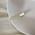 Gros plan d'une pince à cheveux triangulaire crème posée sur une assiette blanche. - Clip Triangulaire Sans Trace (FJ83071) / Beige Translucide