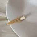 Vue détaillée d'une pince à cheveux crème triangulaire avec texte France Handmade sur plateau - Clip Triangulaire Sans Trace (FJ83071) / Abricot