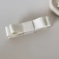 Détail d'une pince à cheveux banane avec nœud en tissu crème pour queue de cheval. - Pince banane à nœud / Beige
