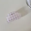 Primer plano de una pinza para el pelo a cuadros rosa transparente sobre fondo claro. - Cuadros Rosas-Pinza Concha