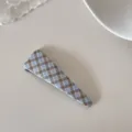 Gros plan d'une barrette BB à carreaux bleu et marron au style rétro pour les franges - Pince Triangle / Carreaux Bleus