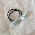 Close-up detail of a light blue fabric bow hair tie on a white crinkled background - Aqua Green