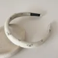 Gros plan d'un serre-tête en tissu crème avec un délicat imprimé de nœud marron - 2cm de Large / Jaune