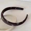 Gros plan d'un serre-tête en tissu marron foncé avec des motifs de nœuds blancs - 2cm de Large / Marron