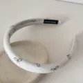 Détail d'un bandeau blanc de style français avec imprimé nœud et étiquette HAND MADE - 2cm de Large / Beige