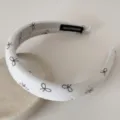 Gros plan d'un serre-tête rembourré blanc de style français avec des motifs de nœuds bruns - 3CM de large / Beige