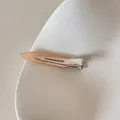 Gros plan d'une pince à cheveux en acétate pêche avec le texte 'FRANCE Handmade' - Orange