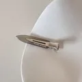Gros plan sur une pince à cheveux en acétate avec texte sur une assiette blanche texturée - Gris Transparent