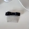 Close-up view of a black fabric bow hair comb featuring white polka dots and silver tines - Black Polka Dot Comb