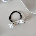 Close-up of a white satin bow hair tie with black polka dots on a minimalist surface - Beige Polka Dot Scrunchie
