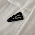 Vue détaillée d'une barrette à cheveux triangulaire à pois noirs et blancs sur tissu blanc - Grand triangle creux / Noir