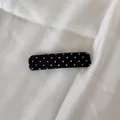 Détail d'une pince à cheveux classique à pois noirs et blancs sur tissu blanc - Pince carrée / Noir