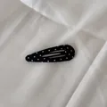 Gros plan détaillé d'une pince à cheveux triangulaire classique à pois noirs et blancs - Clip Goutte d'Eau Ajouré / Noir