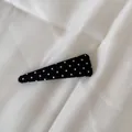 Vue détaillée d'une pince à cheveux triangulaire noire élégante à pois blancs fins. - Petit triangle / Noir